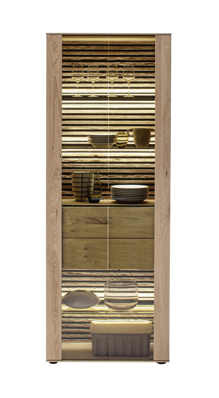 Vitrine aus Holz mit Glastüren, beleuchtet, gefüllt mit Geschirr und Gläsern, frontal betrachtet.