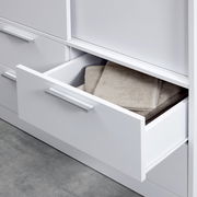 Nahaufnahme eines weißen Schiebetürenschranks mit offener Schublade, gefüllt mit Handtüchern, von der Seite betrachtet.