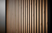 Close-up van een kast met schuifdeuren, verticale houten lamellen en een zwarte achtergrond, gezien vanuit de zijkant
