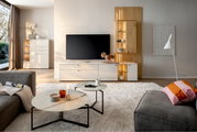 Moderne woonkamerwandcombinatie met tv, witte kasten en houten accenten, gezien vanuit een gezellige woonkamer met bank en salontafels.