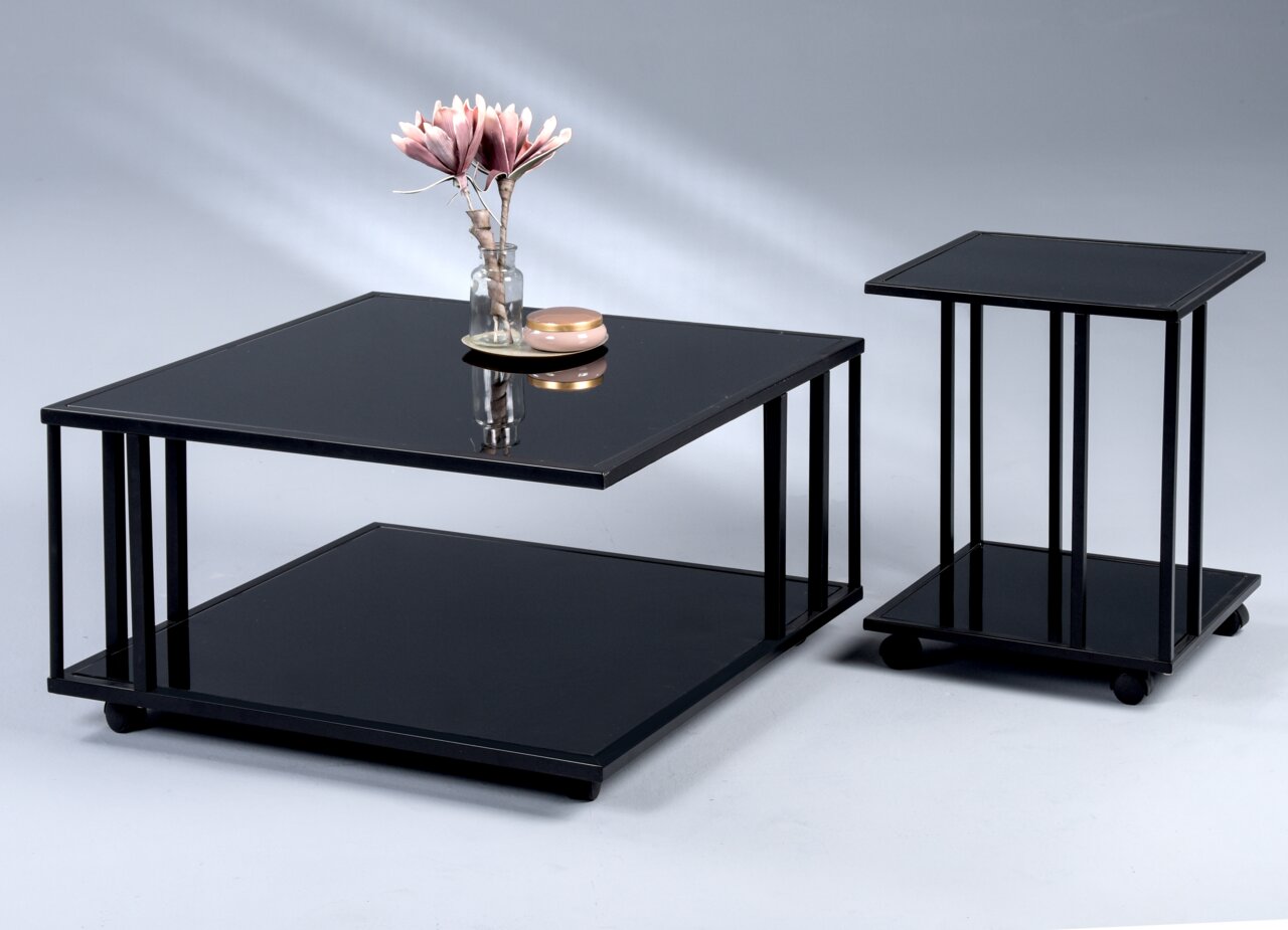 Twee moderne tafels met een zwart glazen blad, een bijzettafel en een salontafel, gefotografeerd vanuit een zijaanzicht.