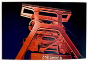Nachtfoto van de rood verlichte schachttoren van de Zollverein-kolenmijn, genomen vanuit een licht opwaarts gericht perspectief.