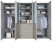 Geöffneter Funktionsdrehtürenschrank mit mehreren Fächern und Schubladen, gefüllt mit Kleidung und Accessoires, frontale Ansicht.