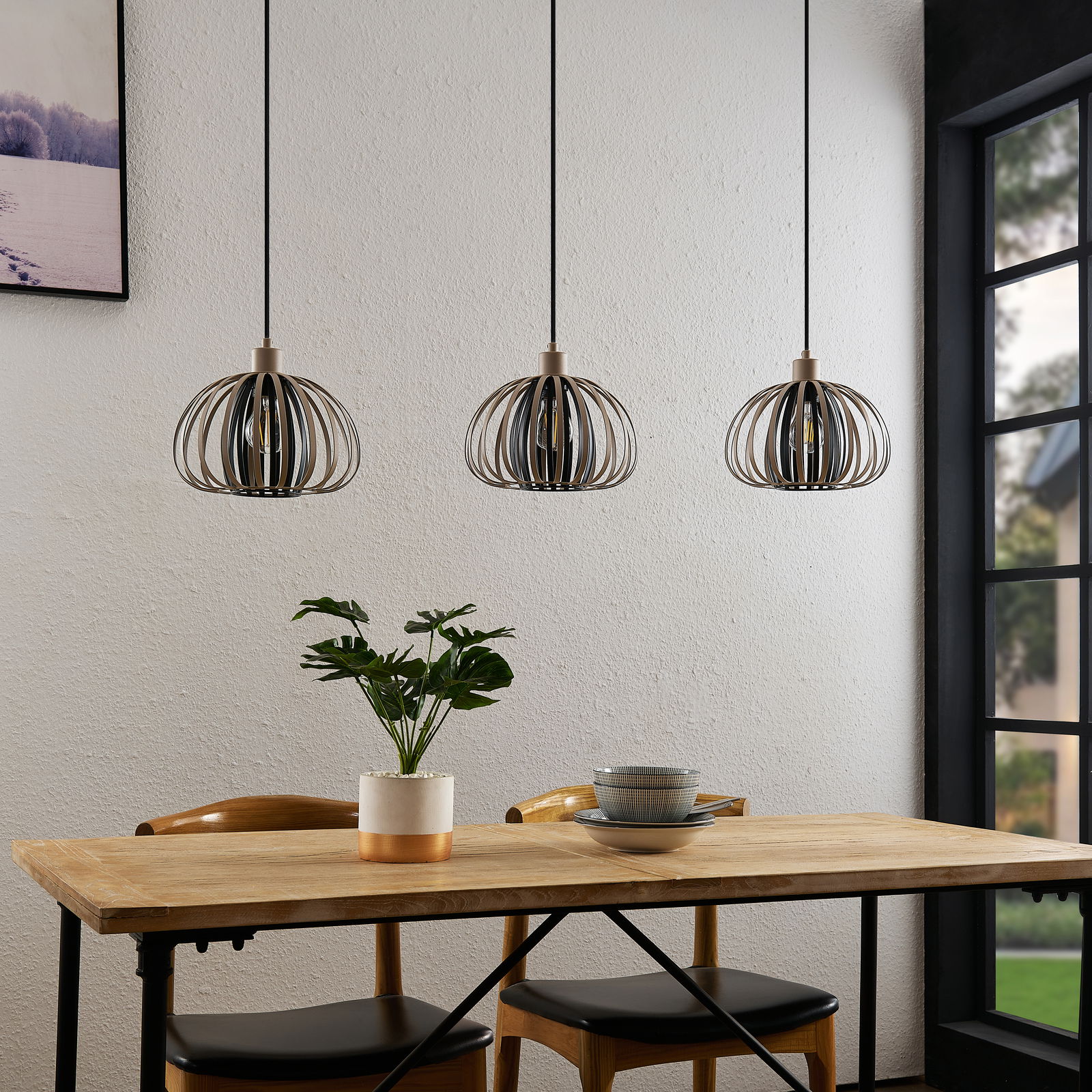 Drei moderne Hängeleuchten mit Metallkäfig-Design über einem Esstisch, seitliche Perspektive.