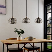 Drie moderne hanglampen met een metalen kooivormig ontwerp boven een eettafel, gezien vanaf de zijkant.