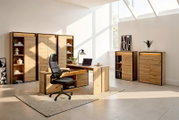 Modernes Homeoffice-Möbelset in natürlicher Holzoptik mit Schreibtisch, Stauraumelementen und beleuchteten Vitrinen, aus frontaler Perspektive in einem lichtdurchfluteten Raum inszeniert.