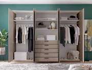 Offener, moderner Kleiderschrank in Beige mit drei Bereichen, Kleiderstangen, Regalböden und fünf Schubladen, gefüllt mit Kleidung und Aufbewahrungsboxen; Frontalansicht.