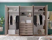 Open, moderne kledingkast in beige met drie vakken, kledingstangen, planken en vijf lades, gevuld met kleding en opbergdozen; vooraanzicht.