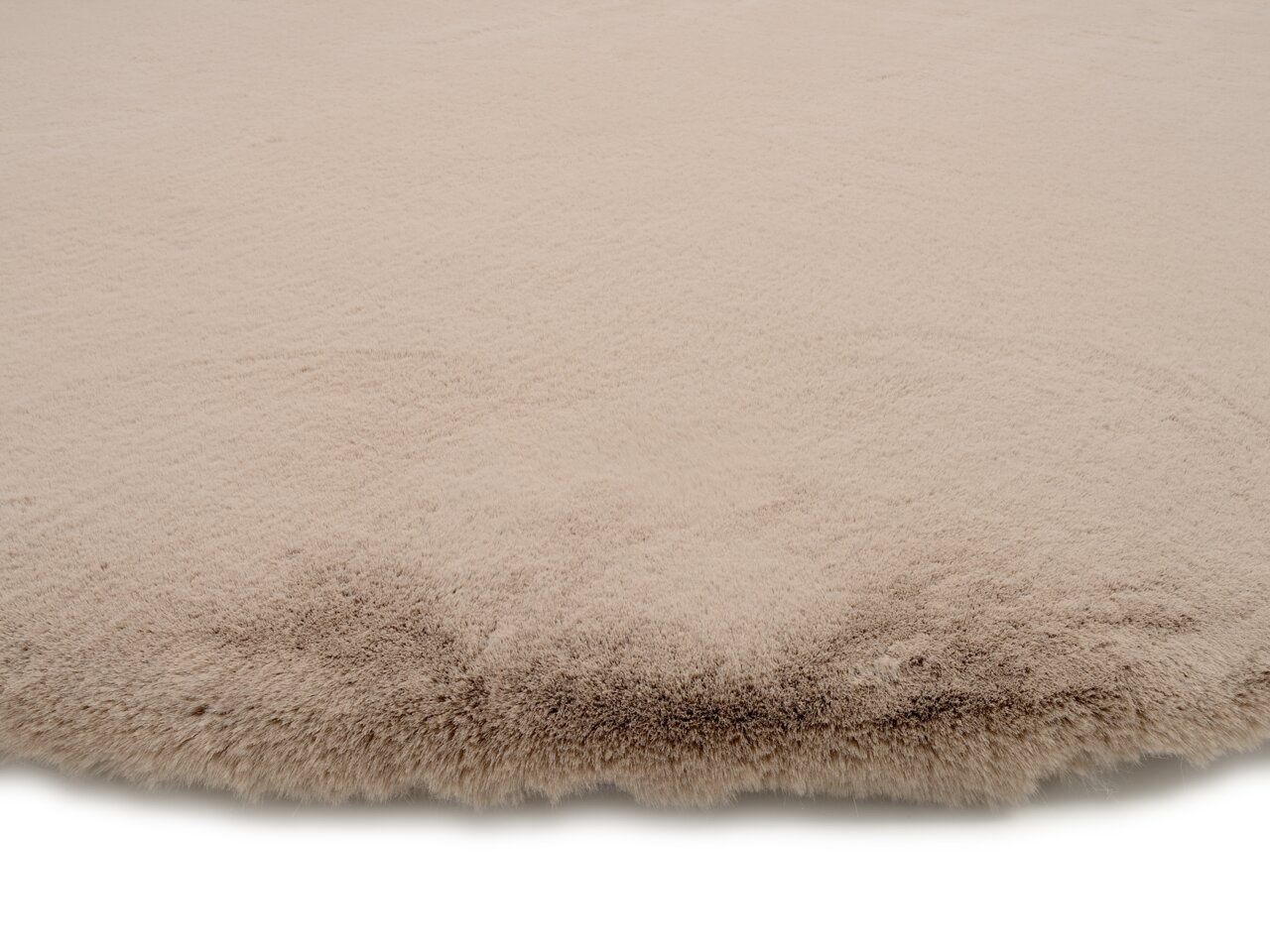 Nahaufnahme eines beigen Fellteppichs mit weicher, flauschiger Textur.