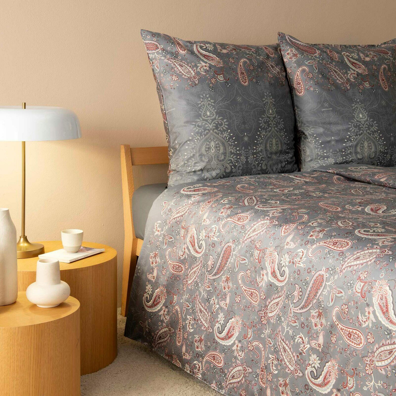 Bettwäsche-Set in Grau mit Paisley-Muster, auf einem Bett mit Holzrahmen, seitliche Perspektive