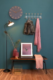Garderobe Wood XL an einer Wand mit einem Mantel und Schal, daneben eine Stehlampe und ein Bild auf einer Bank, aus der Frontalperspektive.