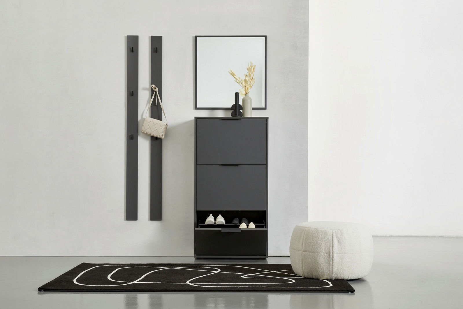 Moderner Eingangsbereich mit schwarzem Schuhkipper, Spiegel und Garderobenpaneel-Set. Perspektive von vorne.