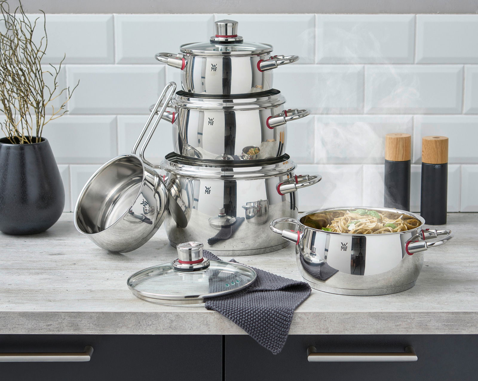 Topfset Quality One 5-tlg. aus Edelstahl, bestehend aus mehreren Töpfen und Deckeln, auf einer Küchenarbeitsplatte präsentiert. Perspektive: Frontalansicht.