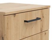 Nahaufnahme einer Kommode aus hellem Holz mit schwarzem Griff, seitliche Perspektive