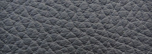 Nahaufnahme der texturierten Oberfläche eines Sessels in dunkler Farbe, diagonale Perspektive.