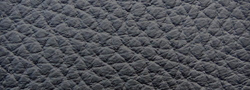 Nahaufnahme der texturierten Oberfläche eines Sessels in dunkler Farbe, diagonale Perspektive.