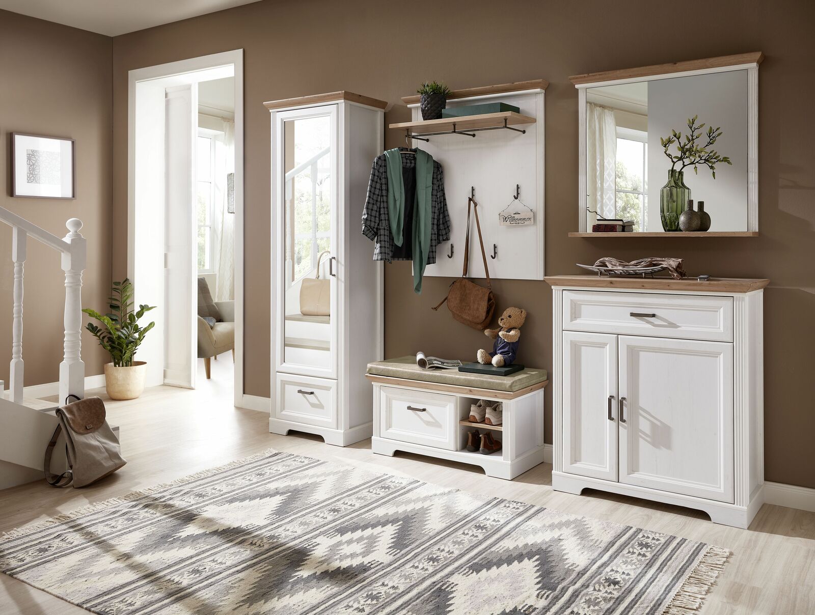 Garderoben-Set JUDITH in einem modernen Flur, bestehend aus einem hohen Schrank mit Spiegel, einer Sitzbank mit Stauraum, einer Wandgarderobe mit Haken und einem großen Spiegel, aus der Perspektive des Eingangsbereichs fotografiert.