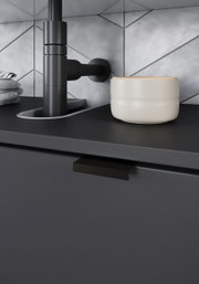 Nahaufnahme eines modernen Waschbeckenunterschranks in dunklem Design mit schwarzem Wasserhahn und cremefarbener Schale, seitliche Perspektive.