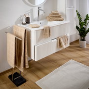Beige badstofset in een moderne badkamer, met handdoeken op een handdoekrek en een wastafel, zijaanzicht