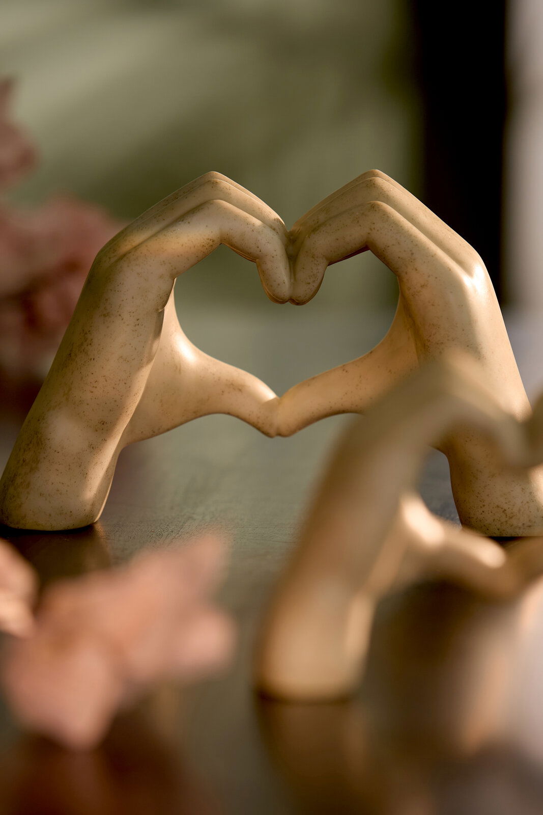 Light&Living Ornament HANDS 15cm Zwei Hände aus Keramik formen ein Herz, auf einem Tisch stehend, mit unscharfem Hintergrund. Perspektive: seitlich.