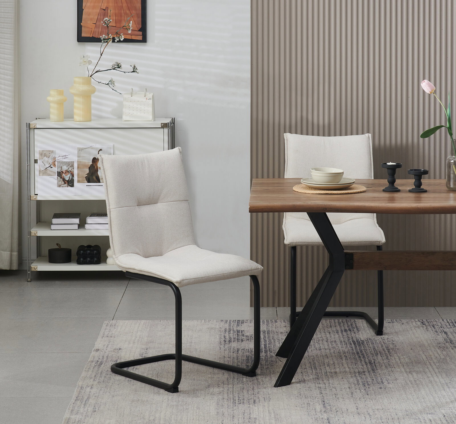 Beiger Polsterstuhl mit schwarzem Metall-Kufengestell neben einem Holztisch mit schwarzem Z-Fuß in modernem Esszimmer, seitliche Perspektive