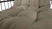 Close-up van een beklede hangstoel in beige, gezien vanaf de zijkant.