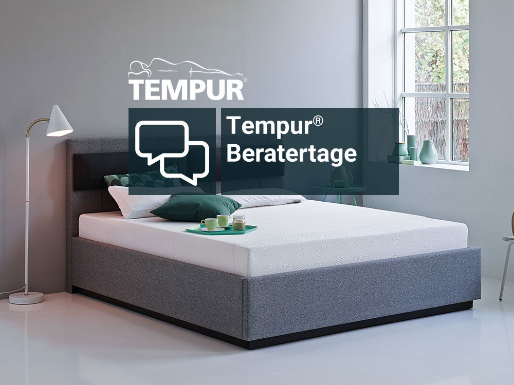 Ein modernes, stilvolles Schlafzimmer mit einer Tempur-Matratze auf einem grauen Polsterbett, mit dekorativen Kissen und einer Stehlampe