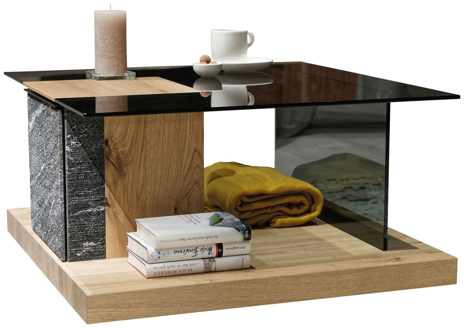 Voglauer Couchtisch V-ROCK Moderner Couchtisch mit Glasplatte, Holz- und Steinelementen, dekoriert mit einer Kerze, einer Tasse und Büchern, aus seitlicher Perspektive.