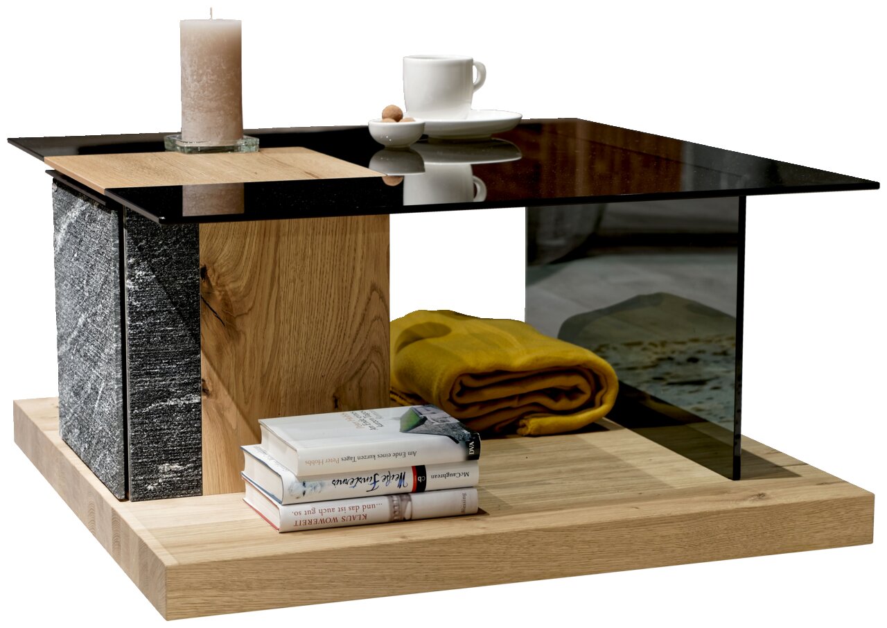 Moderner Couchtisch mit Glasplatte, Holz- und Steinelementen, dekoriert mit einer Kerze, einer Tasse und Büchern, aus seitlicher Perspektive.