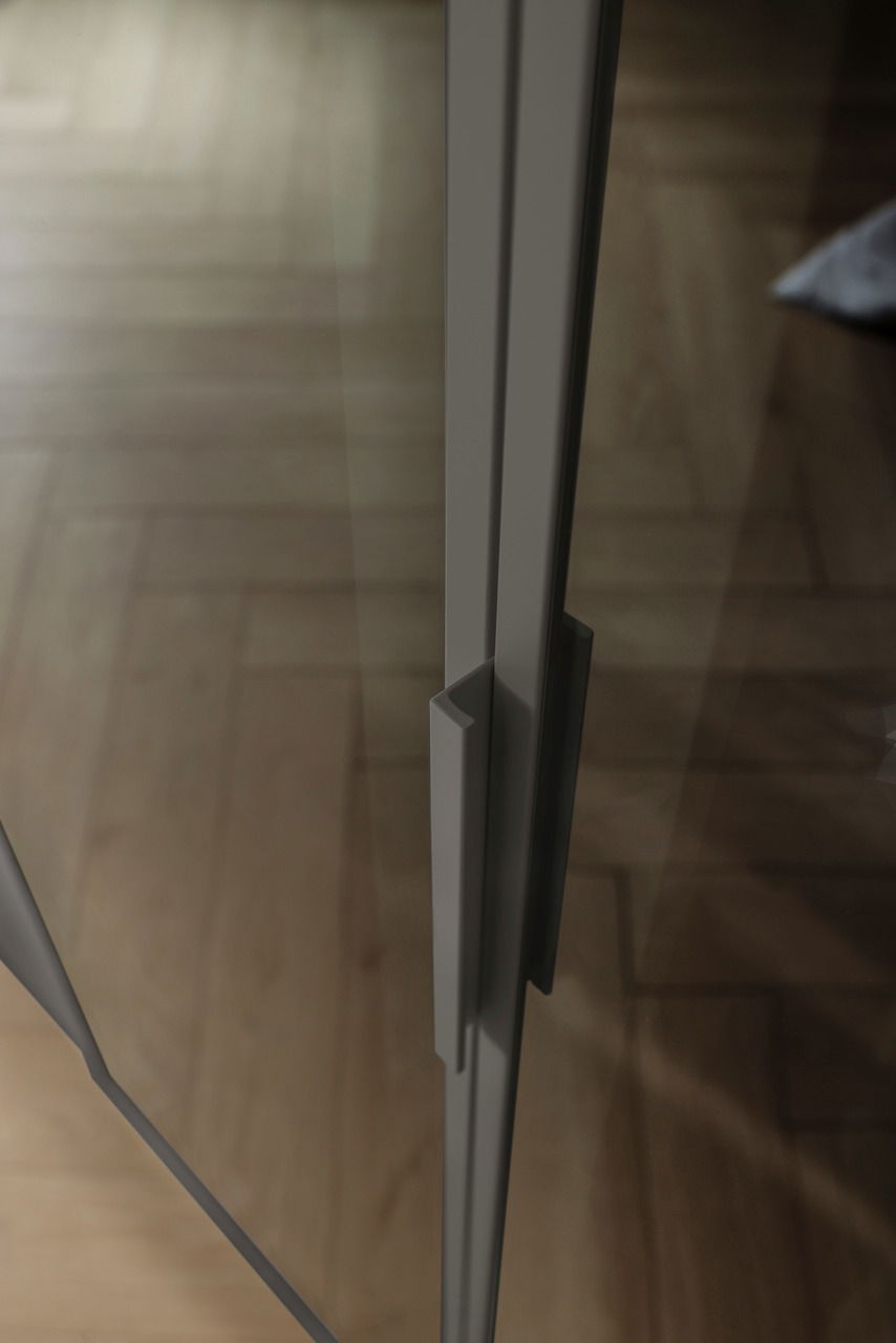 Nahaufnahme eines Griffs an einer Glastür eines sechstürigen Drehtürenschranks, aus seitlicher Perspektive fotografiert.