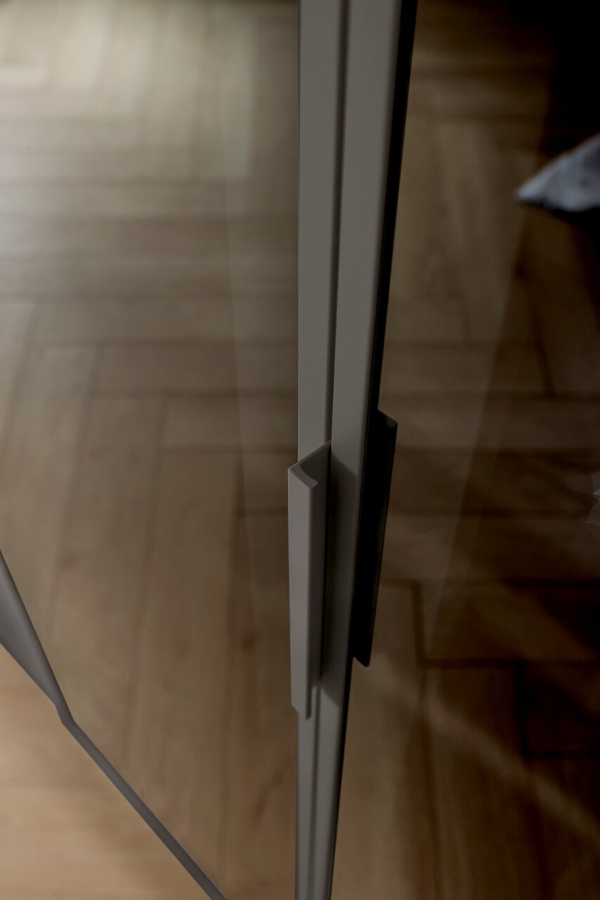 Close-up van een handgreep op een glazen deur van een kast met zes draaideuren, gefotografeerd vanuit een zijaanzicht.