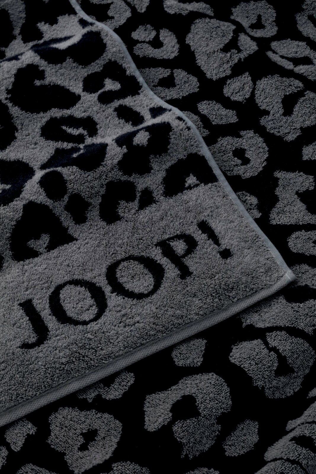 Graues Saunatuch mit schwarzem Leopardenmuster und dem Schriftzug 'JOOP!' in Nahaufnahme.