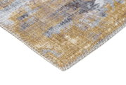 Close-up van een tapijtrand met een abstract patroon in beige- en grijstinten, vanuit een zijdelingse hoek gefotografeerd.