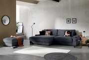 Modernes graues Ecksofa mit Chaiselongue und passendem Hocker in einem stilvollen Wohnzimmer, perspektivisch in leichter Schrägansicht von vorn aufgenommen