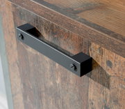 Nahaufnahme eines schwarzen Metallgriffs an einer Holztür mit rustikaler Holzmaserung, seitliche Perspektive