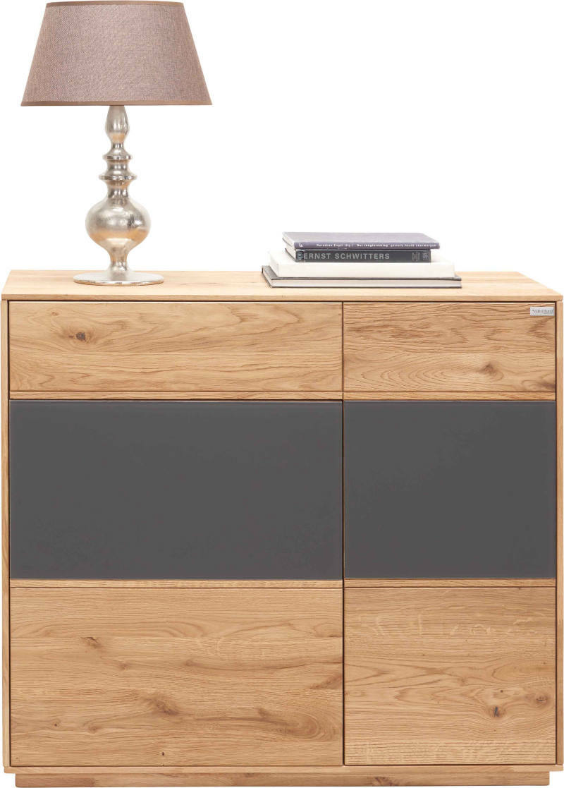 Kommode aus Holz mit grauen Akzenten, darauf eine Tischlampe und Bücher, frontal fotografiert