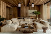 Moderne Akku-Windlicht-Tischleuchte in einem stilvollen Wohnzimmer mit Holzwänden und gemütlichem Sofa, aus der Perspektive von vorne betrachtet.