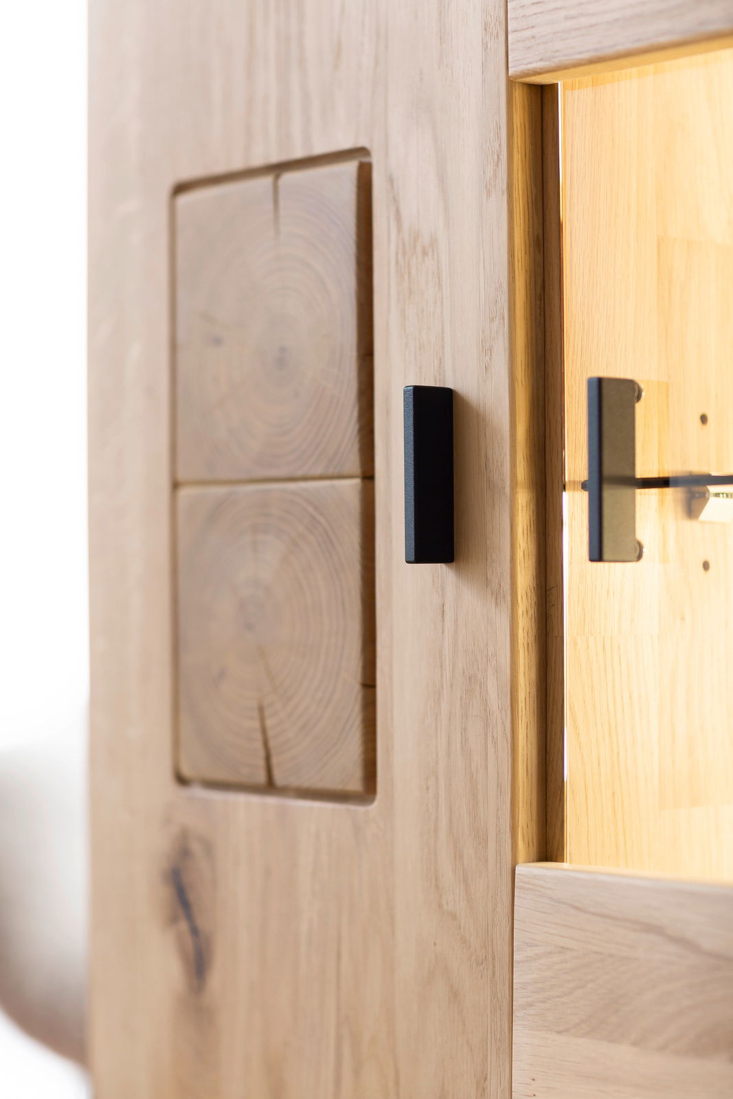 Nahaufnahme einer Holzmöbeloberfläche mit sichtbarer Holzmaserung und einem schwarzen Griff, seitliche Perspektive.