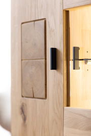 Nahaufnahme einer Holzmöbeloberfläche mit sichtbarer Holzmaserung und einem schwarzen Griff, seitliche Perspektive.