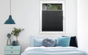 Schwarzes Plissee am Fenster in einem modern eingerichteten Schlafzimmer, seitliche Perspektive