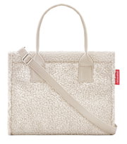 Vooraanzicht van een kleine, crèmekleurige shopper met een zacht, donzig oppervlak en een verstelbare schouderriem.