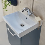 Modernes weißes Keramik-Waschbecken mit verchromter Armatur und Unterschrank in Blau, fotografiert aus schräger Vogelperspektive von oben