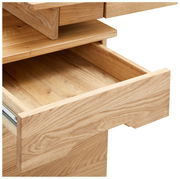 Nahaufnahme eines geöffneten Schreibtischschubfachs aus hellem Holz, von schräg oben fotografiert.