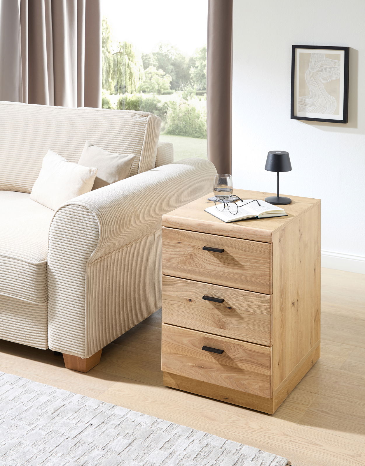 Holz-Rollcontainer mit drei Schubladen, seitliche Perspektive, neben einem Sofa platziert.