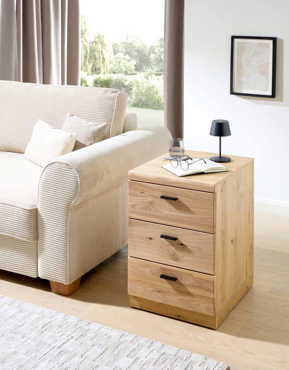 Holz-Rollcontainer mit drei Schubladen, seitliche Perspektive, neben einem Sofa platziert.