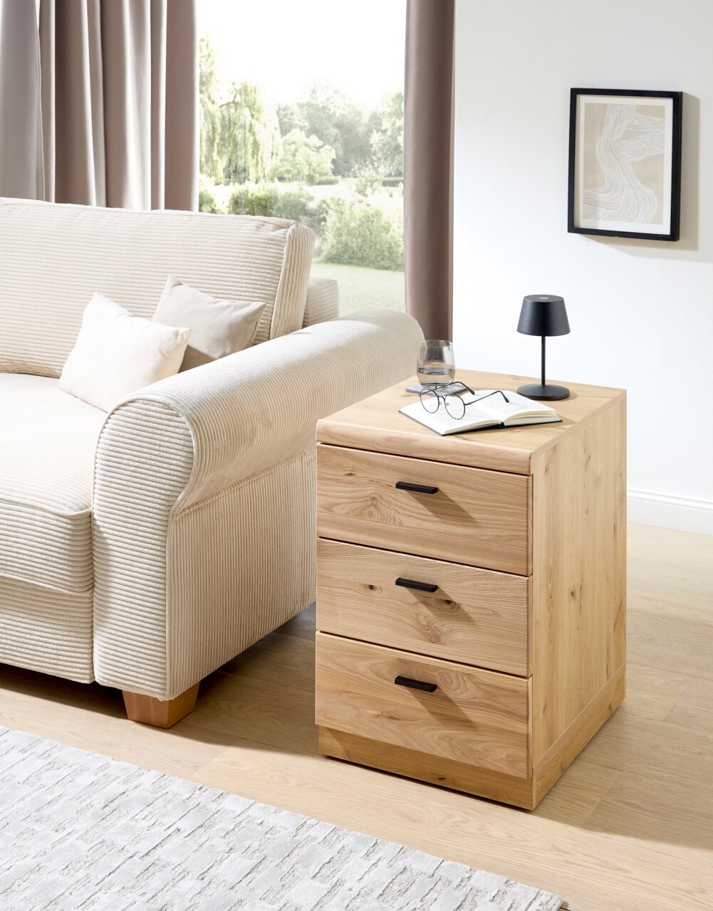 Holz-Rollcontainer mit drei Schubladen, seitliche Perspektive, neben einem Sofa platziert.