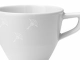 Nahaufnahme einer weißen Espressotasse mit Henkel und dezentem Muster, seitliche Perspektive