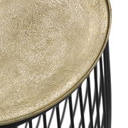 Nahaufnahme eines Beistelltisches mit goldener, strukturierter Oberfläche und schwarzem Drahtgestell, von oben betrachtet.