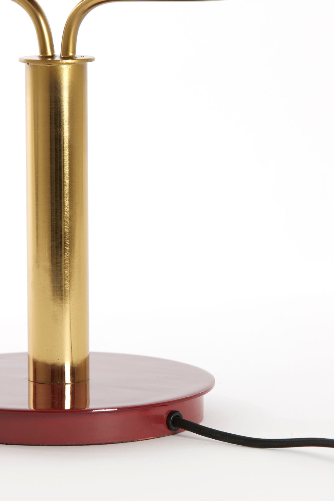 Nahaufnahme einer Tischleuchte mit einem goldenen Ständer und einem roten Sockel, seitliche Perspektive.