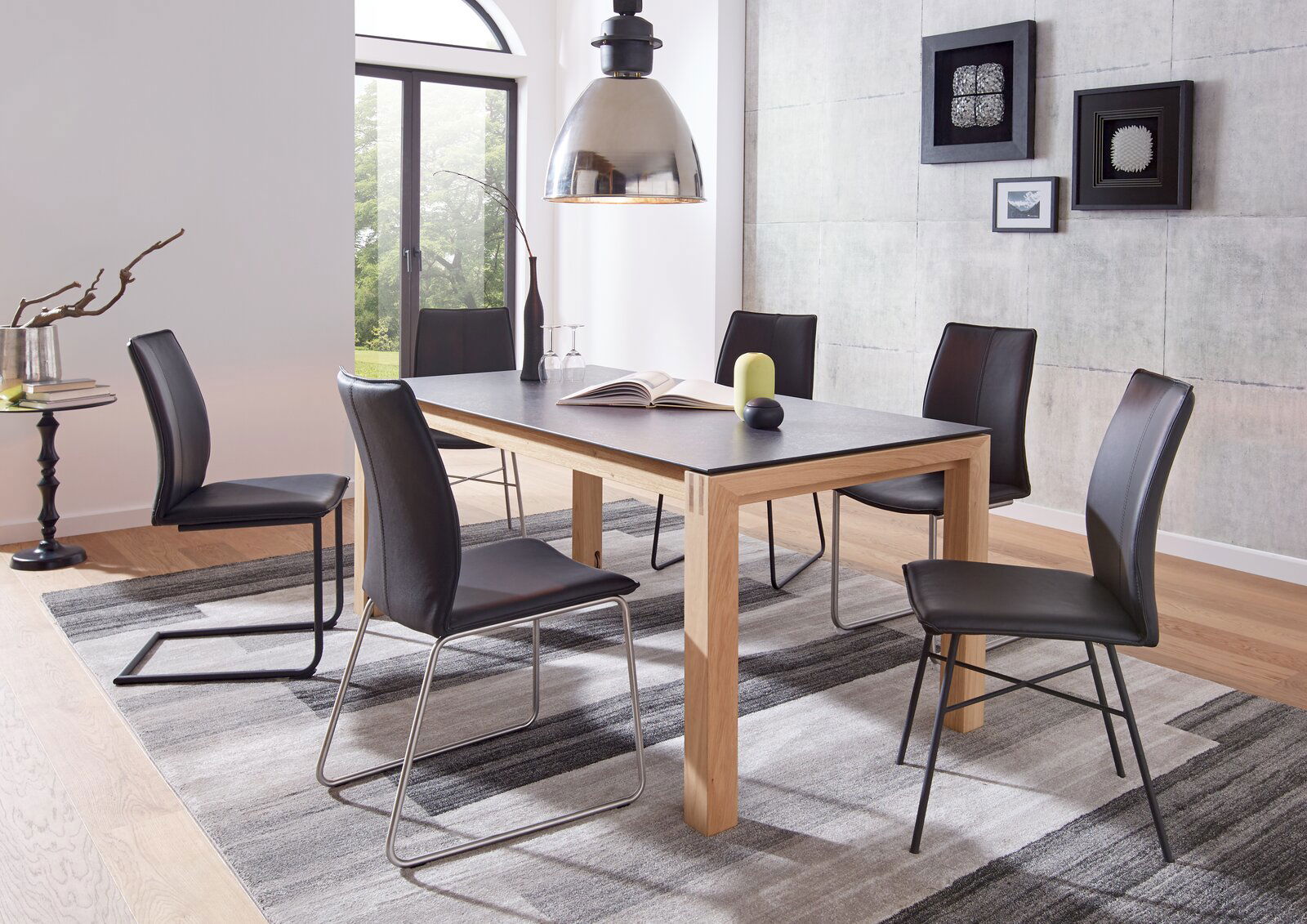 Moderner Essbereich mit einem Esstisch aus Holz und sechs schwarzen Stühlen, seitliche Perspektive.